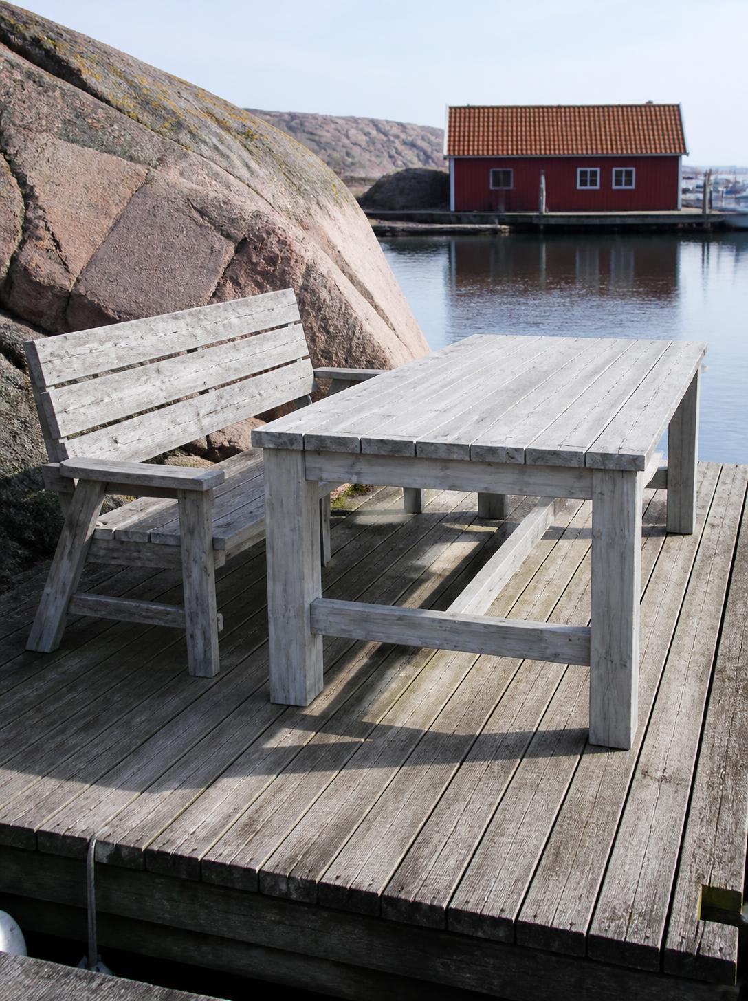 Brygga längs granitklippor i Bohuslän med ett grånat bord